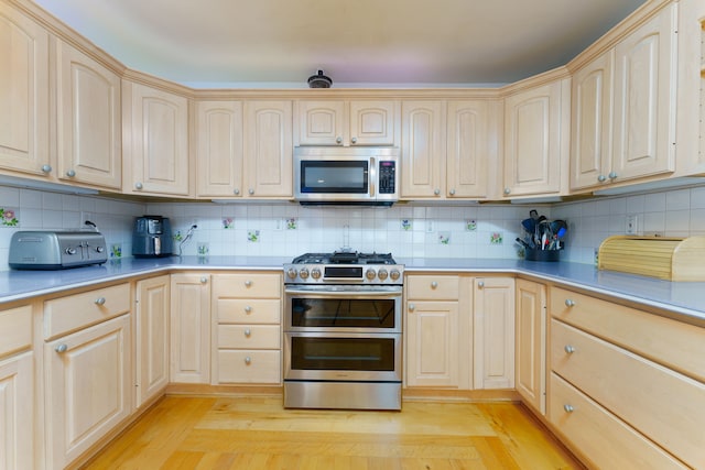 kitchen with light brown cabinetry, decorative backsplash, light hardwood / wood-style flooring, and stainless steel appliances