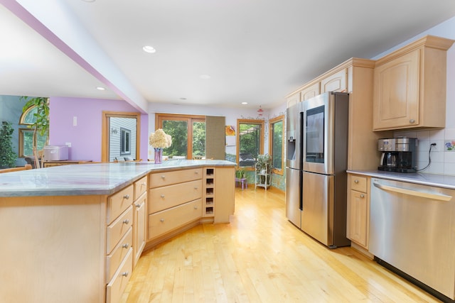 kitchen featuring backsplash, light brown cabinets, stainless steel appliances, and light wood-type flooring