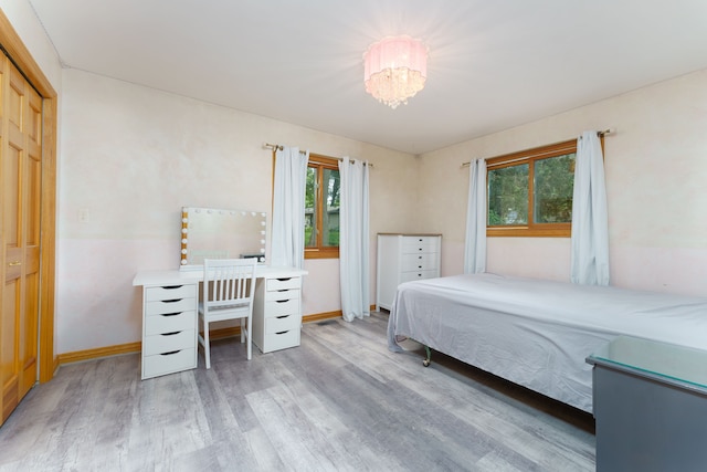 bedroom with an inviting chandelier, wood-type flooring, and a closet