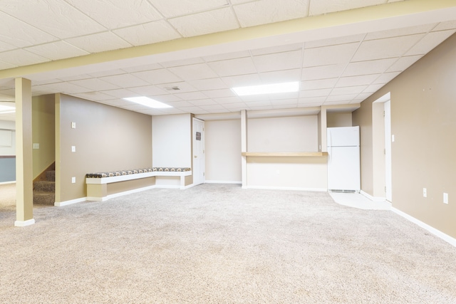 basement featuring carpet, white refrigerator, and a paneled ceiling