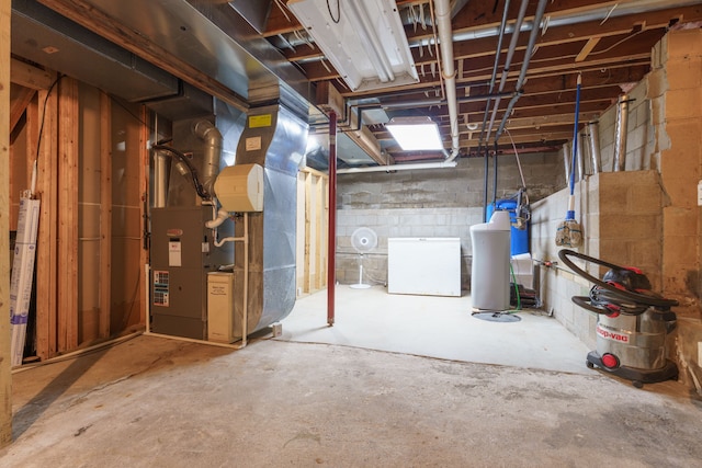 basement featuring white fridge and heating unit