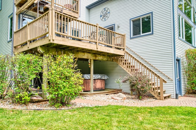 rear view of house with a yard, a hot tub, and a deck