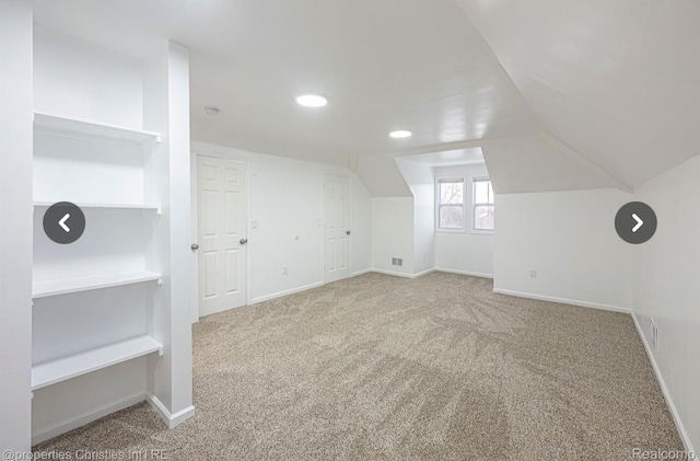 bonus room featuring built in shelves, carpet floors, and vaulted ceiling