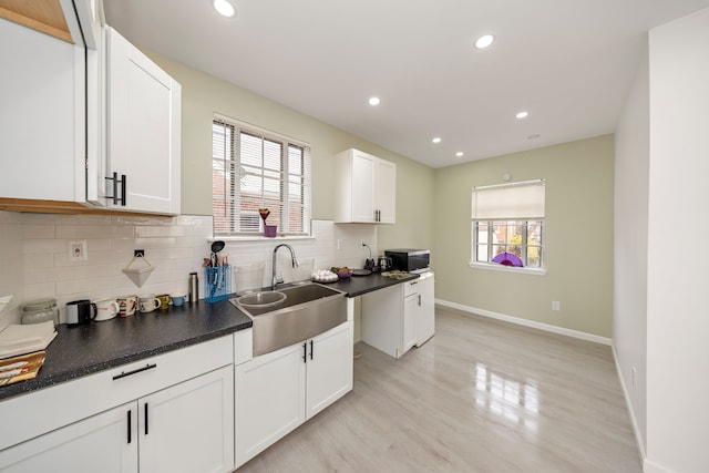 kitchen with white cabinets, light hardwood / wood-style floors, sink, and a wealth of natural light