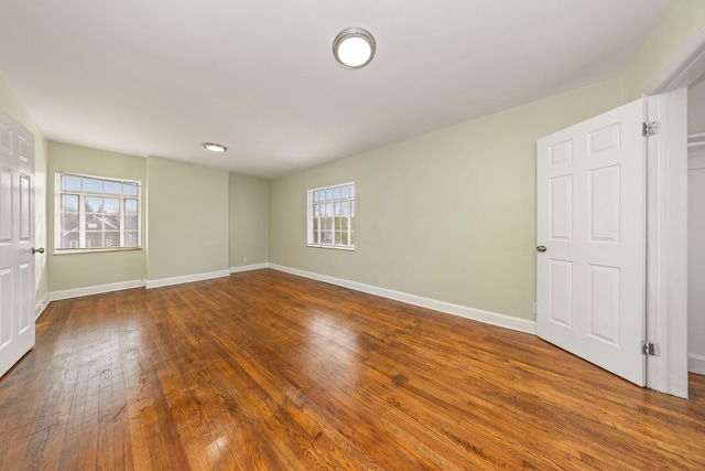 spare room with wood-type flooring and a healthy amount of sunlight