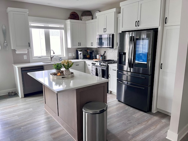 kitchen with stainless steel appliances, white cabinetry, a kitchen island, and sink