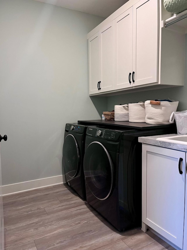 laundry room featuring light hardwood / wood-style flooring, cabinets, and washing machine and clothes dryer