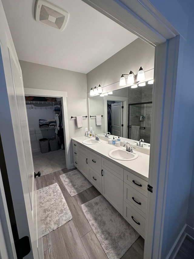 bathroom with wood-type flooring, vanity, and a shower with shower door