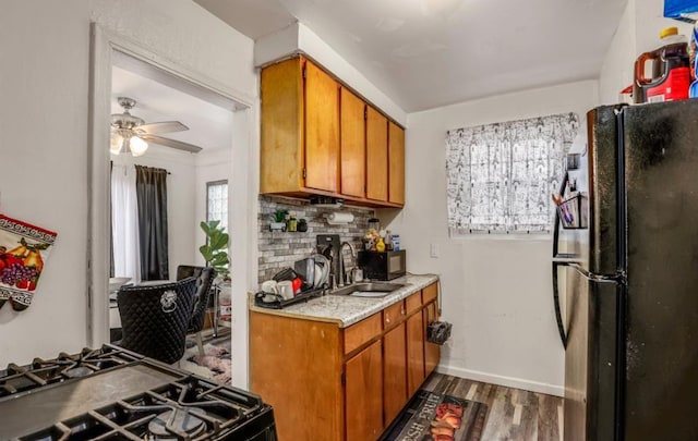 kitchen featuring decorative backsplash, dark hardwood / wood-style flooring, ceiling fan, sink, and black appliances