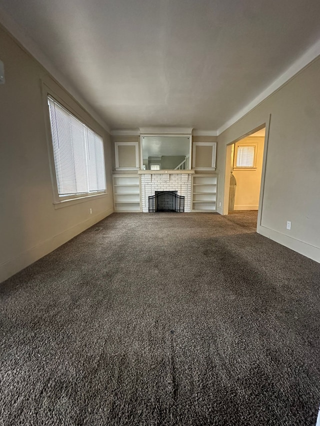 unfurnished living room with built in shelves, carpet floors, and a fireplace