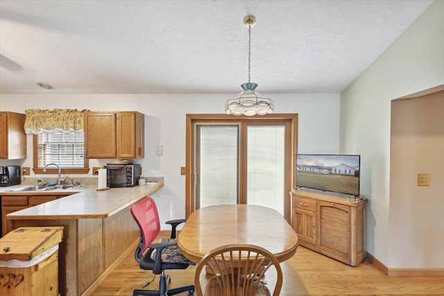 dining area featuring a textured ceiling, light wood-type flooring, and sink