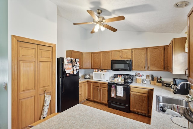 kitchen featuring high vaulted ceiling, black appliances, sink, light hardwood / wood-style flooring, and ceiling fan