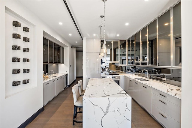 kitchen with light stone countertops, dark hardwood / wood-style flooring, a spacious island, and decorative light fixtures