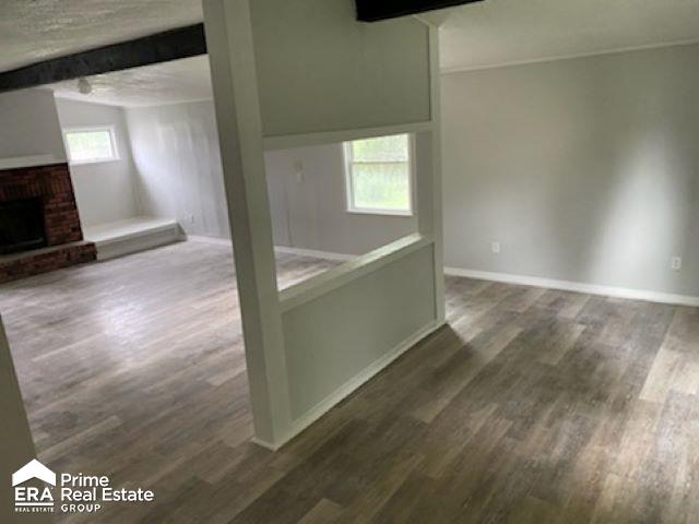 interior space with beamed ceiling, dark hardwood / wood-style floors, a fireplace, and a healthy amount of sunlight