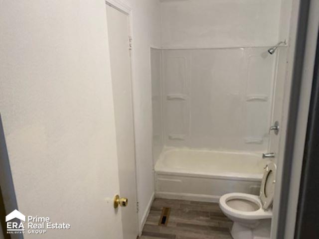 bathroom featuring wood-type flooring,  shower combination, and toilet