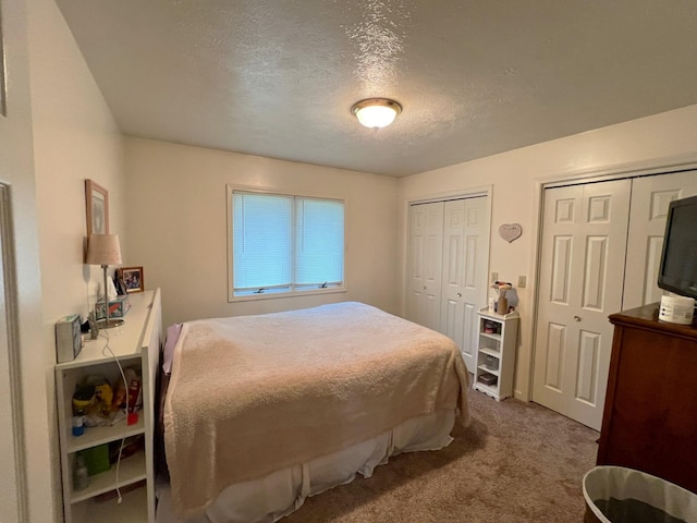 carpeted bedroom with multiple closets and a textured ceiling