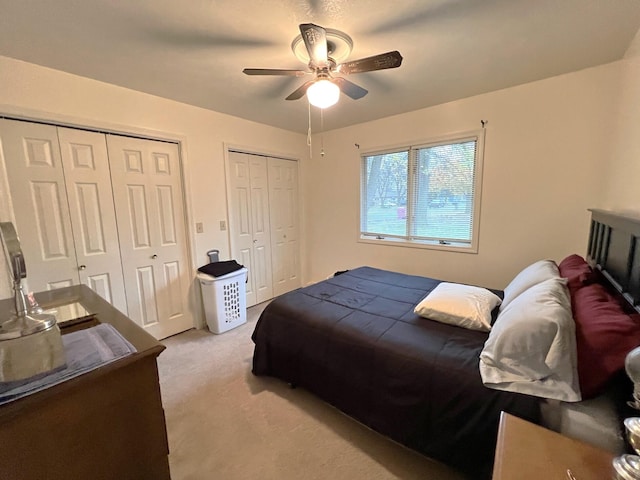 bedroom with multiple closets, ceiling fan, and light carpet