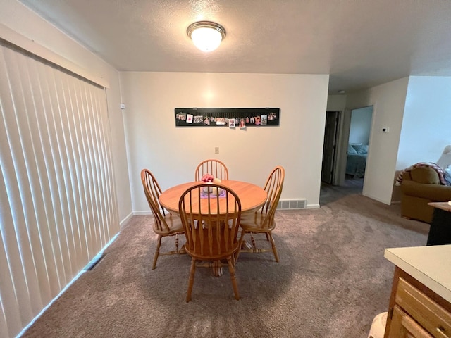 carpeted dining space featuring a textured ceiling