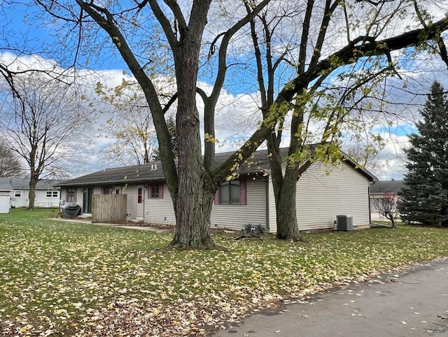 view of property exterior with central AC and a lawn