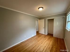 unfurnished bedroom featuring a closet, light hardwood / wood-style floors, and ornamental molding