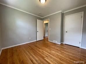 unfurnished bedroom with hardwood / wood-style floors and ornamental molding