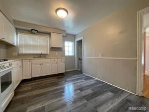 kitchen with white cabinetry, dark hardwood / wood-style flooring, white range, and sink