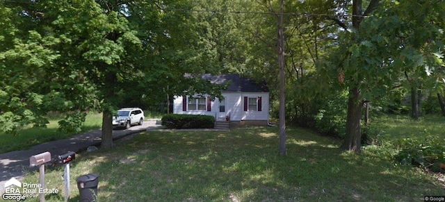 view of property hidden behind natural elements featuring a front lawn