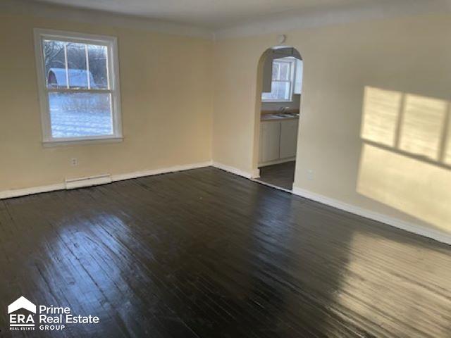 empty room with sink, a baseboard radiator, and dark hardwood / wood-style floors