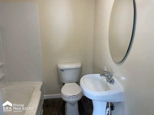 bathroom with a bathing tub, toilet, and sink