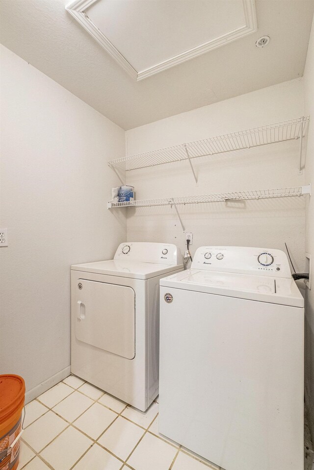 laundry area with light tile patterned floors and washing machine and clothes dryer