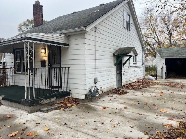 view of side of property featuring a porch, an outdoor structure, and a garage