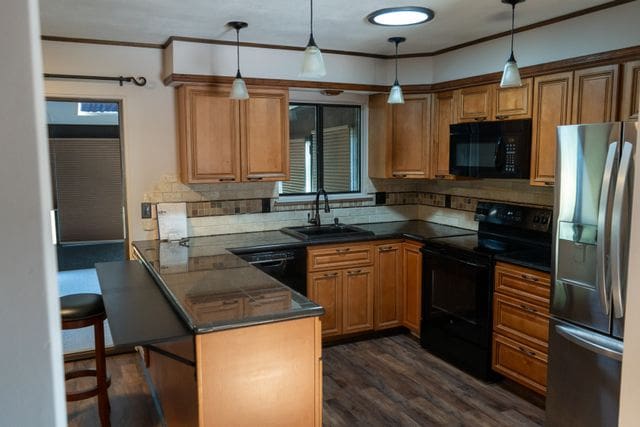 kitchen featuring black appliances, dark hardwood / wood-style floors, pendant lighting, and sink