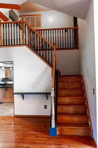 stairs featuring hardwood / wood-style flooring and vaulted ceiling