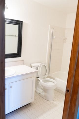 full bathroom with washtub / shower combination, tile patterned flooring, vanity, and toilet