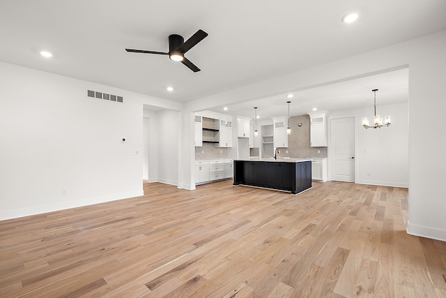 kitchen featuring sink, pendant lighting, light hardwood / wood-style floors, a center island with sink, and white cabinets