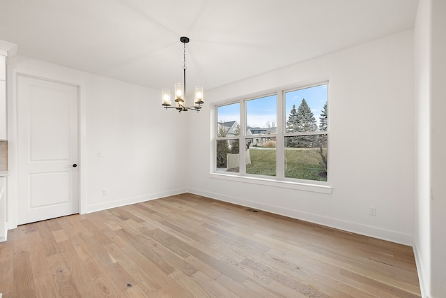 unfurnished dining area featuring light wood-type flooring and an inviting chandelier