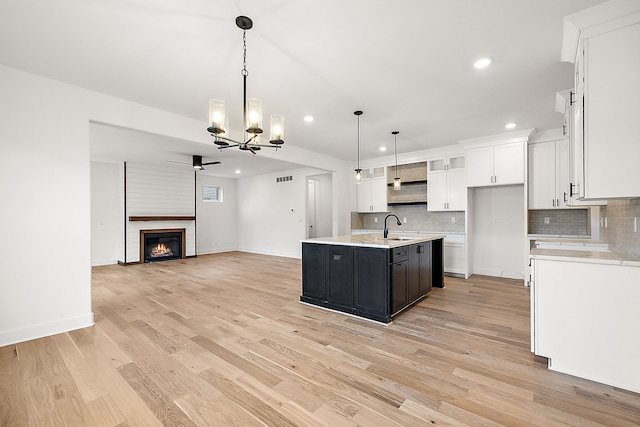 kitchen with ceiling fan with notable chandelier, sink, decorative light fixtures, a center island with sink, and light hardwood / wood-style flooring