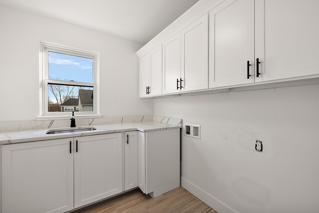 washroom with washer hookup, light hardwood / wood-style floors, cabinets, and sink