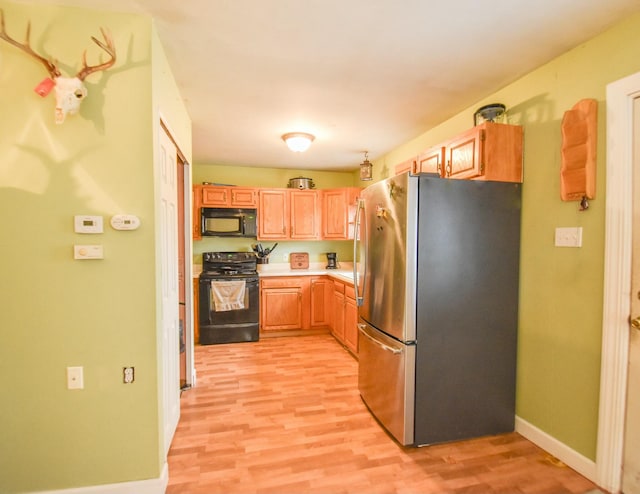 kitchen featuring light wood-type flooring and black appliances