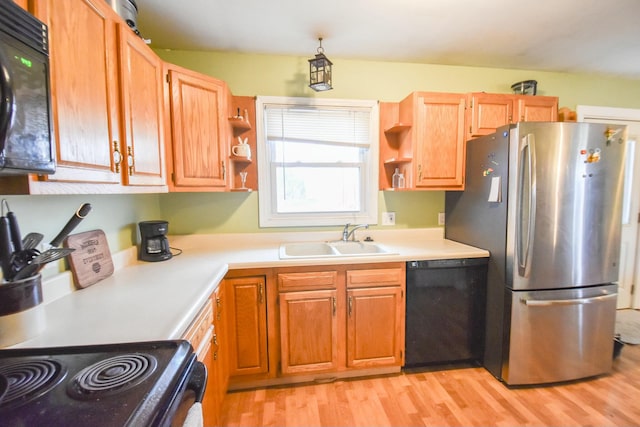 kitchen with sink, black appliances, and light hardwood / wood-style floors