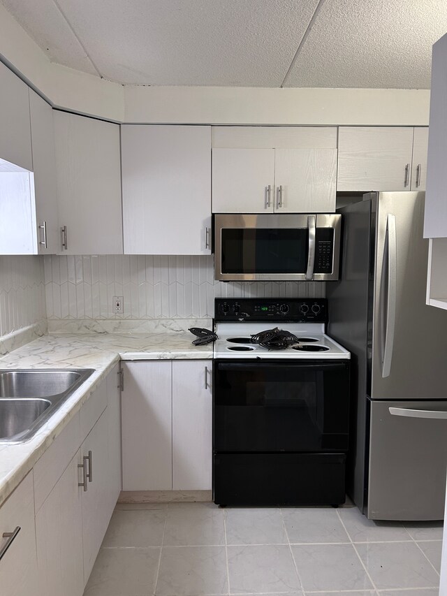 21800 Morley Ave Unit 101, Dearborn, MI 48124 - kitchen with appliances with stainless steel finishes, white cabinets, a sink, tasteful backsplash, and light tile patterned floors