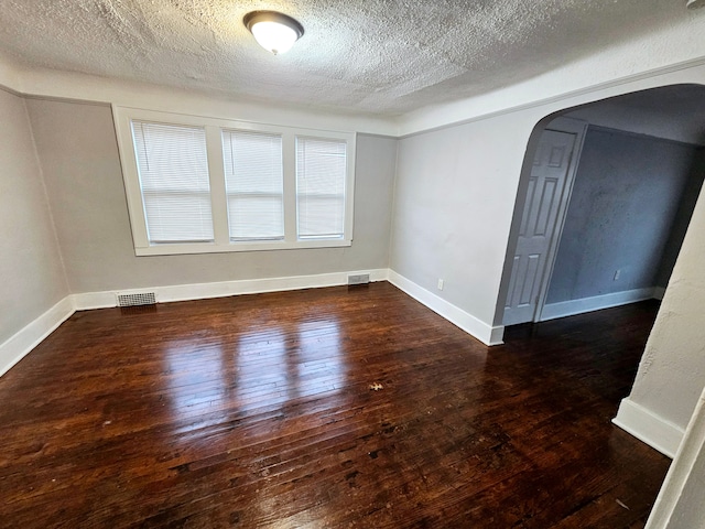 unfurnished room featuring dark hardwood / wood-style flooring and a textured ceiling