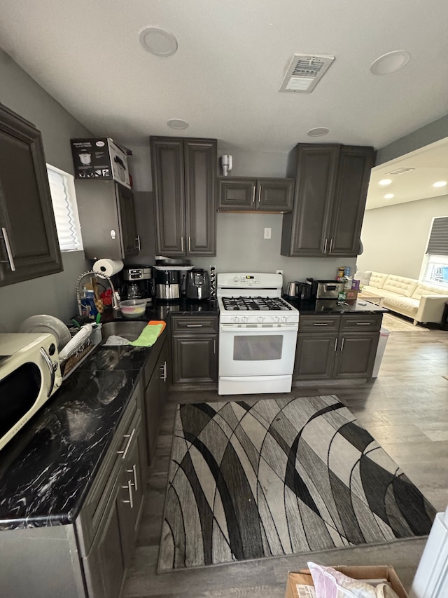 kitchen featuring dark brown cabinetry, light hardwood / wood-style flooring, gas range gas stove, and sink