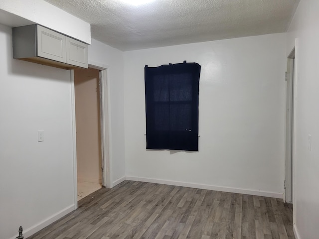 spare room featuring a textured ceiling and light hardwood / wood-style floors