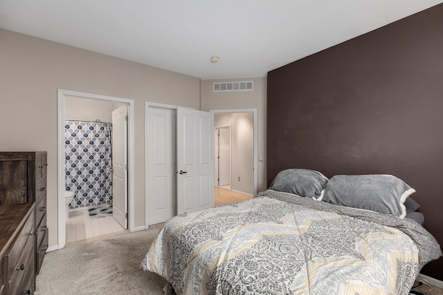 bedroom featuring light carpet and connected bathroom