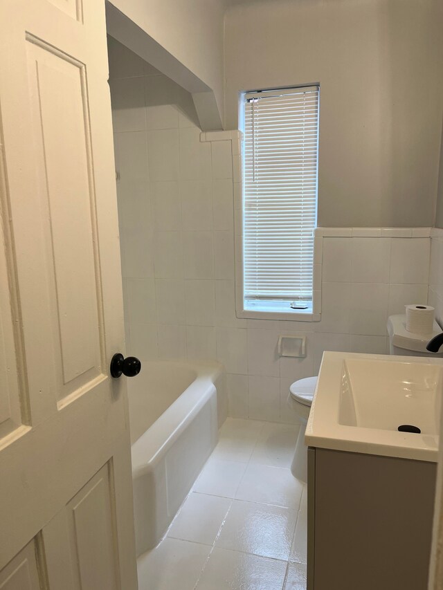 bathroom featuring tile patterned flooring, vanity, tile walls, toilet, and a washtub