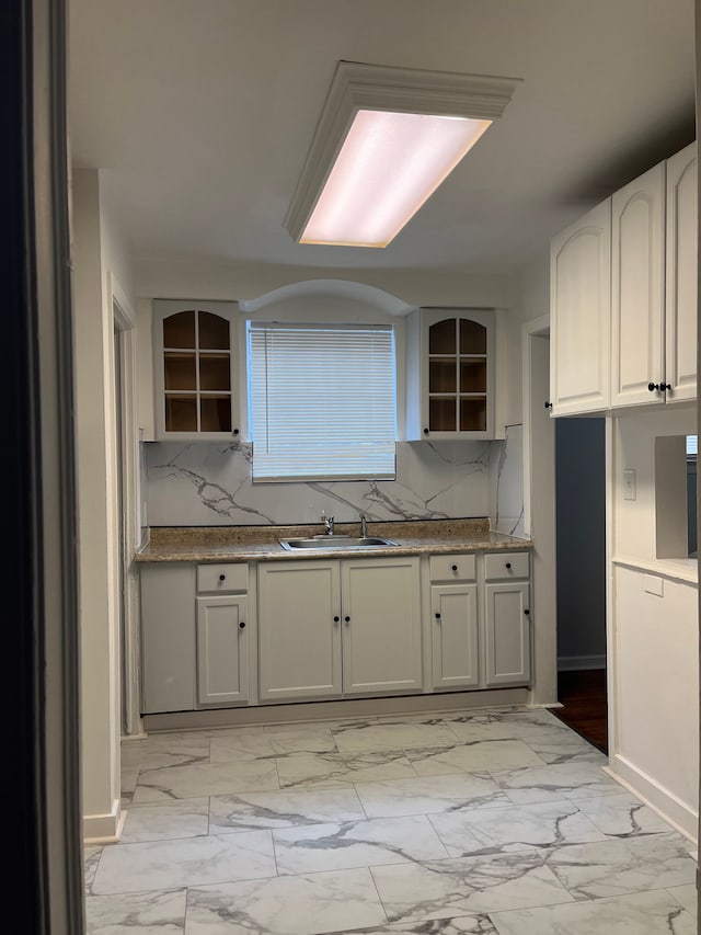 kitchen featuring sink, white cabinetry, stone counters, and decorative backsplash