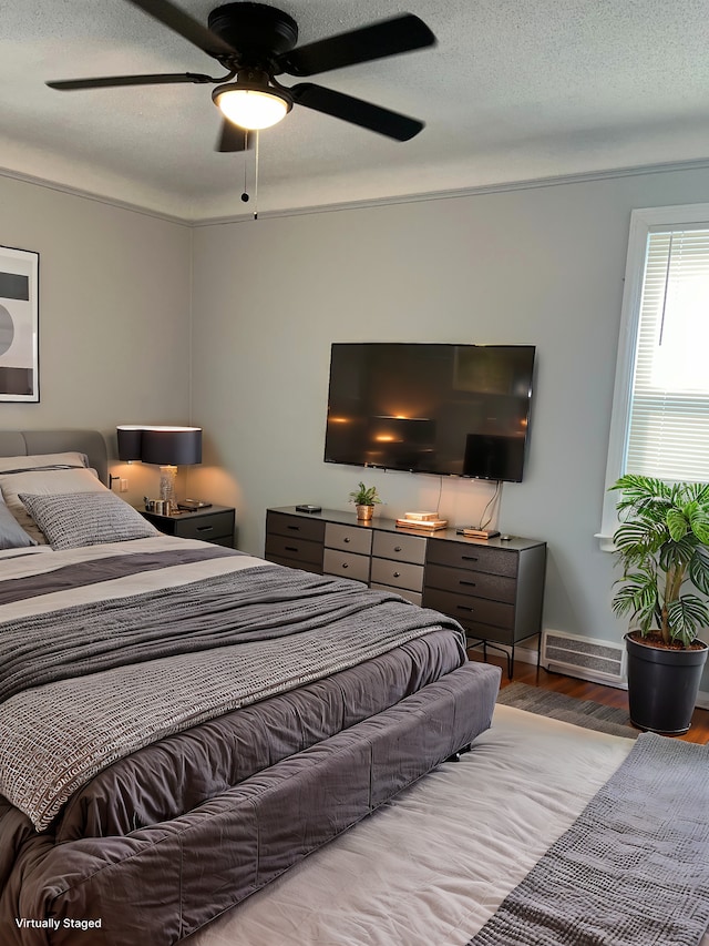 bedroom with ceiling fan, hardwood / wood-style floors, and a textured ceiling