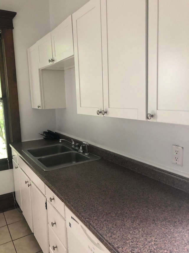 kitchen featuring sink, light tile patterned floors, tasteful backsplash, white dishwasher, and white cabinets