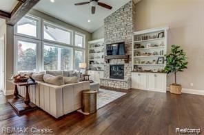 living area with high vaulted ceiling, a stone fireplace, wood finished floors, built in features, and baseboards